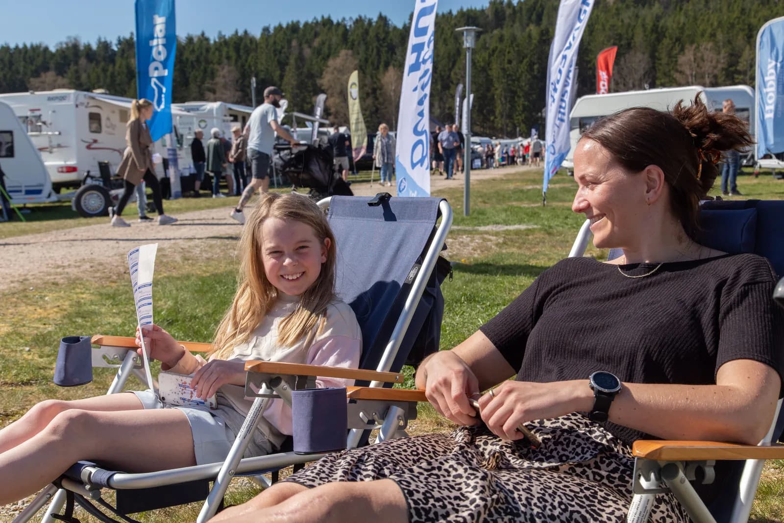 Besökare som vilar i solstolar på mässområdet
